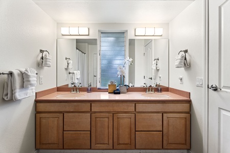 Unwind in your spacious bathroom featuring dual vanities and warm wood cabinetry—perfect for your morning routine.