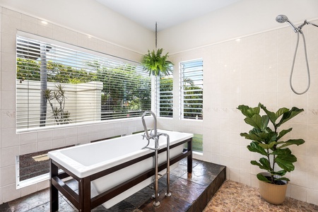 Serene bathroom sanctuary with a deep soaking tub and corner windows, ideal for slow mornings and post-beach resets.