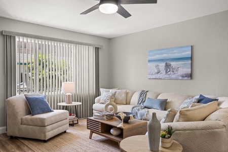 The living area features an airy ambiance with plush sectional sofas, TV and ceiling fan.