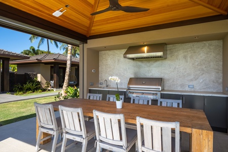 Host memorable gatherings in your covered outdoor kitchen with premium grill, spacious dining table, and tropical garden views.
