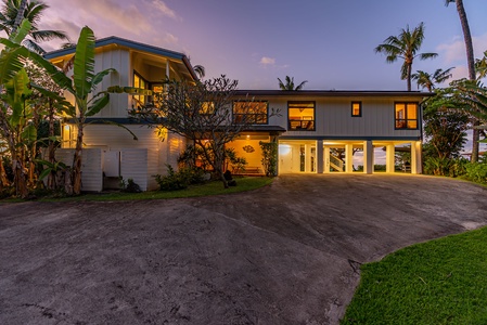 The front entrance welcomes you with a grand driveway and lush tropical plants.