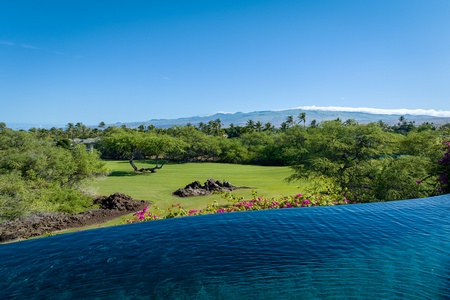 Infinity pool with a stunning view of lush greenery and distant mountains.