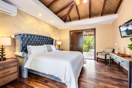 Beautifully appointed bedroom with plush furnishings, hardwood floors, and tropical views.