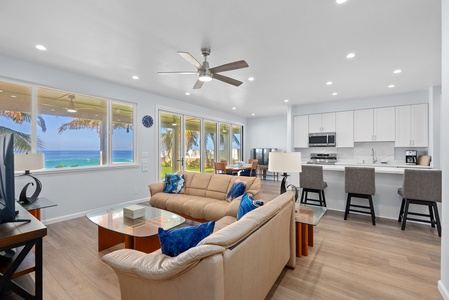 Lower-level living area with coastal textures, ceiling fan, and wall-to-wall ocean views.