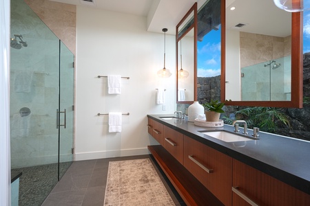 Bright bathroom featuring dual sinks and a glass-enclosed shower with a garden view.