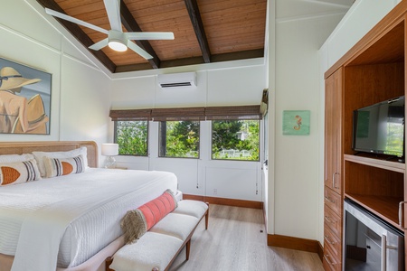 Private exterior-access bedroom with a king bed, vaulted ceilings, and garden views.