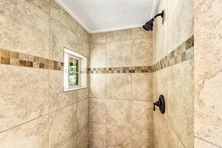 Walk in shower with window looking out to the green scape