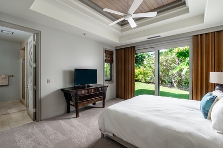 Guest bedroom with direct access to the outdoors, ceiling fan, and comfortable king-sized bed.