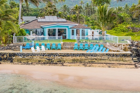 Take in a full view of your beachfront retreat from the water, showcasing expansive outdoor seating, oceanfront lawn space, and uninterrupted coastal scenery.