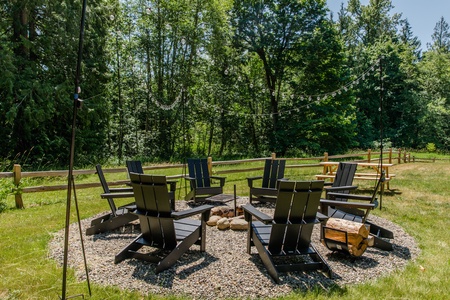 Gather around the spacious fire pit surrounded by towering evergreens and five acres of private woodland, creating the perfect setting for evening conversations beneath the stars.