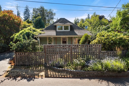 The front porch and garden showcase the home’s classic architecture and charm, inviting guests to relax and enjoy the peaceful ambiance.