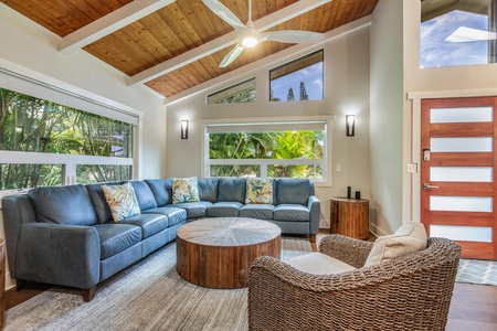 Lounge in the living area with plush sectional sofas, TV, large glass windows and high vaulted ceiling.