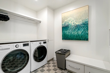 Your private laundry room features full-size washer and dryer with hanging space and cheerful ocean artwork for a pleasant chore experience.