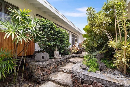 Lava-rock landscaping and tropical plants line the walk to the entry.