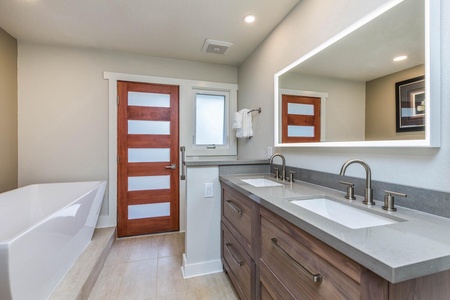 An ensuite bathroom at Lani Oasis with double vanity, sleek fixtures, and warm wood cabinetry.