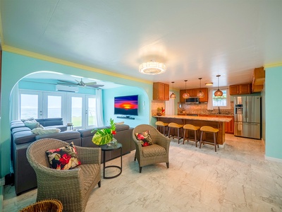 Step into a bright, tropical living space featuring turquoise walls, comfortable seating, and a fully equipped kitchen designed for gathering, meals, and relaxed island living.