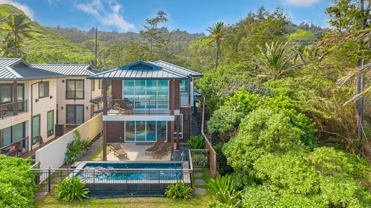 Dining table positioned by windows offering beautiful views of the ocean and lush tropical greenery.