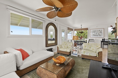 Your tropical-inspired cottage living room has wicker furniture, ceiling fan, and bright windows creating a breezy island atmosphere.