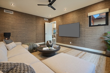 Media room with plush seating, large TV, and soft natural lighting.