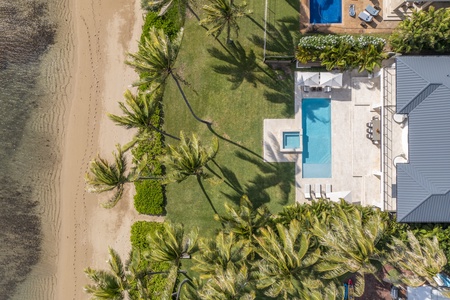 Overhead view of the estate framed by palms, pool, and oceanfront setting.