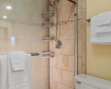 The third bathroom features a walk-in shower with sleek tile and fresh towels.