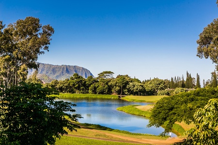 A serene golf course surrounded by peaceful water features and mountains.