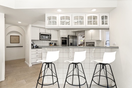 Sleek white cabinetry, stainless steel appliances, and a breakfast bar perfect for morning coffee.