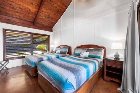 Second guest bedroom features twin beds, vaulted ceilings, and a breezy tropical vibes.