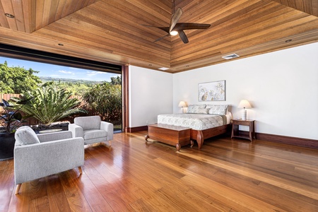 Wake up in your stunning guest suite with warm wood ceilings, elegant furnishings, and seamless garden views through floor-to-ceiling glass doors.