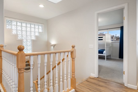 Step into your bright upstairs hallway where natural light floods through glass block windows, leading to comfortable bedrooms perfect for restful nights.