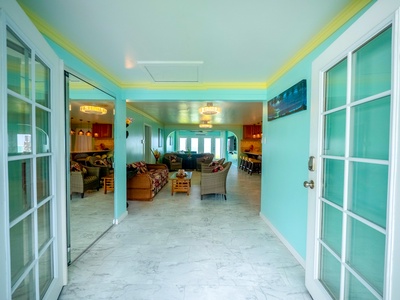 Step into your vibrant tropical retreat where turquoise walls and elegant chandeliers create an inviting atmosphere for relaxation.