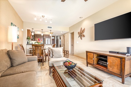 Living area toward the kitchen showcasing large wall mounted smart flat screen TV.