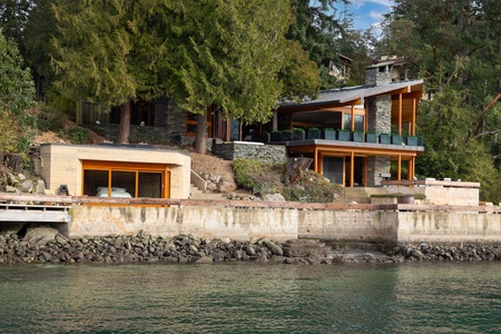 Stunning waterfront retreat surrounded by lush forest and serene waters.