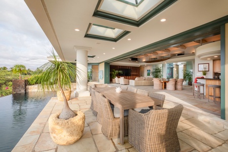Covered lanai with elegant dining and lush scenery—host unforgettable meals outdoors.