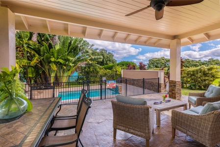 Poolside seating area at Pohaku Villa, offering a relaxing spot beside lush landscaping.