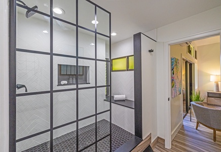 The spacious walk-in shower features modern black-framed glass panels, a convenient built-in bench, and stylish tile work that combines elegance and functionality