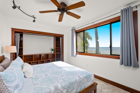 Comfortable bedroom with a queen-sized bed, wood furnishings, and large windows.