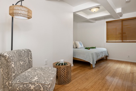 A cozy corner bedroom features warm wood floors, soft linens, and natural light—ideal for a restful night or quiet retreat.