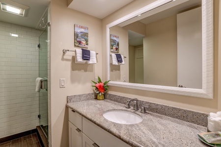 The bathroom at Papakea B-105 includes a granite vanity and modern fixtures for comfort.