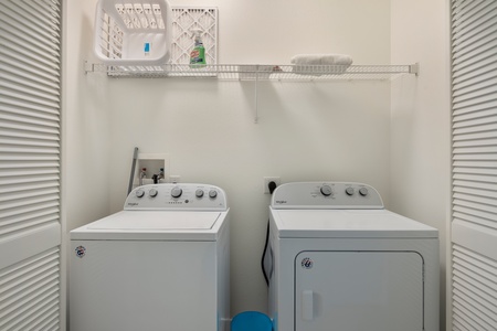 Laundry room includes a washer, dryer, overhead shelf, and space for beach gear.