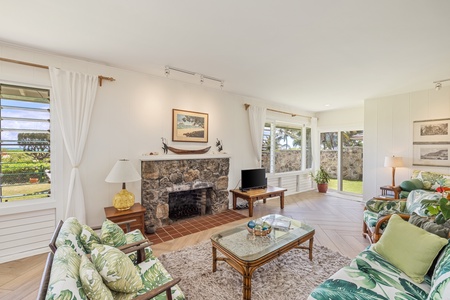 Cozy up in this inviting corner of the home, featuring a charming stone fireplace and serene garden views through the large windows