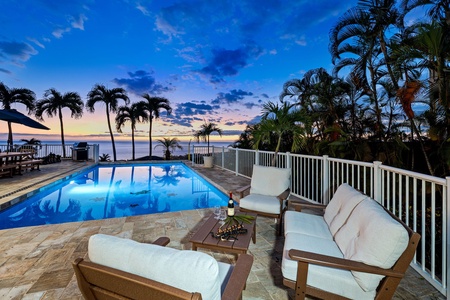 Spectacular oceanfront pool deck with tropical palms frames dramatic sunset views over endless blue waters.