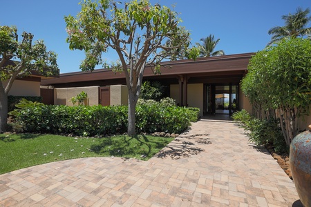 Charming front walkway lined with greenery, offering a warm island welcome.