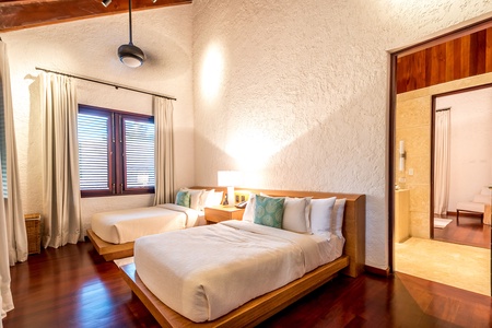 This guest bedroom has two queen beds and warm lighting.