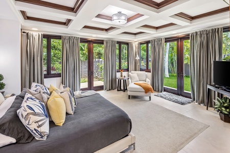 This guest suite features French doors that open to natural light and lush outdoor views.
