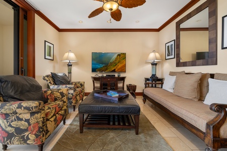 Living area with a flat-screen TV, central AC and plush sofas.