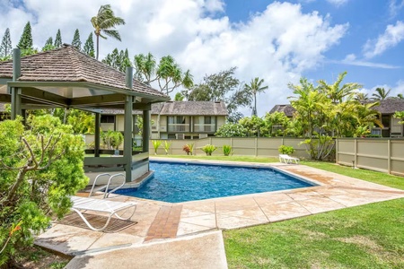 Community pool surrounded by tropical landscaping.