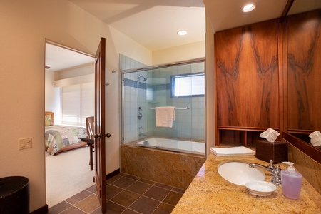Elegant shared second bathroom featuring a glass-enclosed shower and rich wood accents.