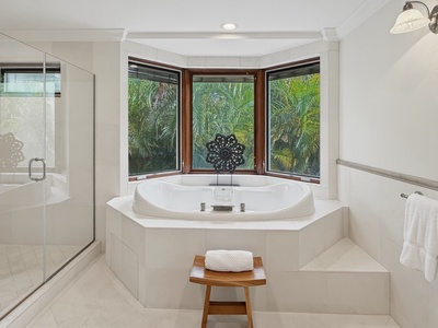 Luxurious soaking tub surrounded by tropical palms, where relaxation meets paradise through panoramic windows.