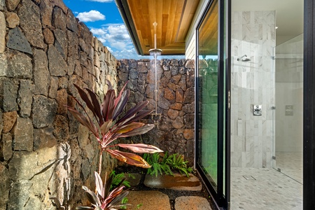 Step into your private outdoor shower oasis, where tropical plants and stone walls create a spa-like sanctuary under the open sky.